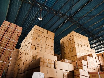 Endless warehouse aisle with rows of identical pallets receding to a vanishing point.